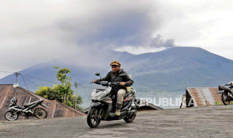 Seorang pengendara motor melintas saat Gunung Marapi memuntahkan material vulkanik saat terjadi letusan di Agam, Sumatera Barat, Indonesia, Senin, 4 Desember 2023. Gunung berapi tersebut memuntahkan kolom abu tebal setinggi 3.000 meter (9.800 kaki) ke langit di letusan mendadak pada hari Minggu dan awan abu panas menyebar beberapa mil (kilometer).