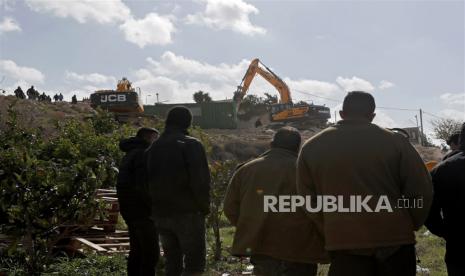  Orang-orang menyaksikan buldoser Israel menghancurkan pemukiman Palestina Nasser Amera di lingkungan Yerusalem Timur di Tsur Baher, Rabu (1/2/2023).  Menteri keamanan nasional Israel Ben Gvir pada 29 Januari memerintahkan untuk mempersiapkan pembongkaran segera bangunan di Yerusalem Timur menyusul serangan terhadap Yerusalem sinagoga 27 Januari.