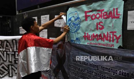 Seorang suporter memasang poster dalam aksi keprihatinan Tragedi Stadion Kanjuruhan. Manajemen Arema FC memastikan crisis center Tragedi Kanjuruhan tetap dibuka.