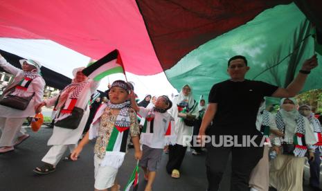 Peserta aksi mebawa bendera Palestina raksasa.