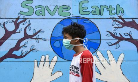 Seorang laki-laki menggunakan masker melintas dekat mural bertuliskan ‘’save earth’’ di Lingkungan Peresak Tempit, Kelurahan Ampenan Tengah, Mataram, NTB, Minggu (5/4/2020). Berdasarkan data Dinas Kesehatan Provinsi NTB jumlah kasus warga terkonfirmasi positif COVID-19 di wilayah NTB yang tersebar di Kota Mataram, Lombok Tengah, Lombok Timur dan Kabupaten Sumbawa hingga Minggu (5/4) pukul 14