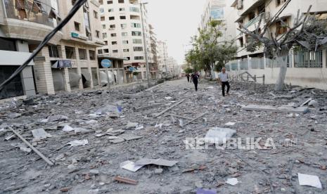 FILE - Dalam file foto 17 Mei 2021 ini, orang-orang memeriksa puing-puing bangunan komersial yang hancur dan klinik perawatan kesehatan Gaza menyusul serangan udara Israel di lantai atas bangunan komersial dekat Kementerian Kesehatan di Kota Gaza. 