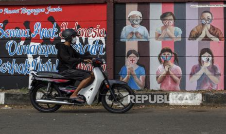 Pengendara sepeda motor melintas di dekat mural bergambar simbol orang berdoa menggunakan masker yang mewakili umat beragama di Indonesia  di kawasan Juanda, Kota Depok, Jawa Barat, Kamis (18/6/2020). Mural yang dibuat oleh warga itu bertujuan untuk memberikan edukasi kepada masyarakat untuk menggunakan masker sebagai salah satu  pencegahan dan penyebaran COVID-19