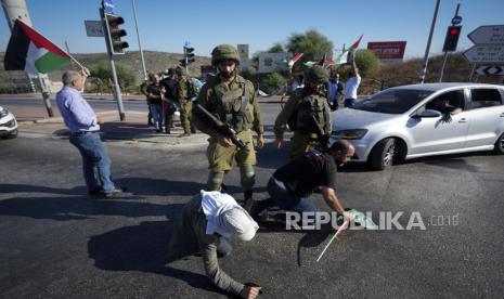 Warga Palestina dan aktivis perdamaian Israel melarikan diri dari gas air mata yang ditembakkan oleh pasukan keamanan Israel, selama demonstrasi menentang pemukiman Yahudi Tepi Barat, dekat kota Salfit, Tepi Barat, Rabu, 27 Juli 2022.