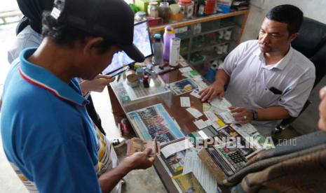 Seorang petani menebus pupuk subsidi di kios penyalur.