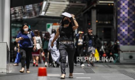 Seorang wanita menutupi wajahnya dengan buku di tengah hari yang panas di Kuala Lumpur, Malaysia, (27/4/2023). Malaysia diperkirakan akan mengalami cuaca panas berkepanjangan hingga Agustus, menyusul musim peralihan monsun, menurut pernyataan Menteri Energi dan Sumber Daya Alam Nik Ahmad.