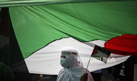 Seorang pengunjuk rasa berdiri di bawah bendera Palestina besar selama unjuk rasa anti-Israel di luar Kedutaan Besar AS di Jakarta, Indonesia, Selasa, 18 Mei 2021. 