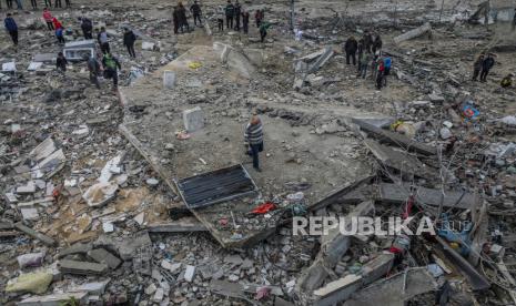 Warga Palestina mencari orang hilang di bawah reruntuhan rumah keluarga Al Hajj yang hancur akibat serangan udara Israel, di kamp pengungsi Al Nusairat, Jalur Gaza selatan, (19/3/2024).