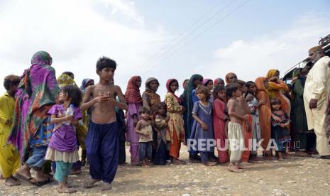 Keluarga pengungsi berbaris untuk menerima makanan saat mereka berlindung di pinggir jalan setelah melarikan diri dari rumah mereka yang dilanda banjir di kota Sohbat Pur, sebuah distrik di provinsi Baluchistan barat daya Pakistan, Selasa, 30 Agustus 2022. Pejabat bencana mengatakan hampir setengah juta orang di Pakistan memadati kamp-kamp setelah kehilangan rumah mereka dalam banjir yang meluas yang disebabkan oleh hujan monsun yang belum pernah terjadi sebelumnya dalam beberapa pekan terakhir. Korban Meninggal Banjir Pakistan Bertambah, Total 1.343 Orang