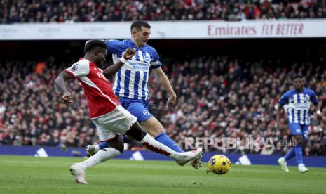 Pemain Brighton Lewis Dunk menghalau aksi bintang Arsenal Bukayo Saka (kiri) di Stadion Emirates, London, Ahad (17/12/2023). 