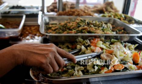 Pekerja melayani pengunjung yang hendak makan di salah satu rumah makan.