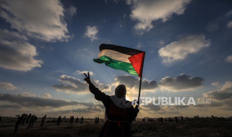  Pengunjuk rasa wanita tua Palestina mengangkat bendera Palestina selama bentrokan di dekat perbatasan antara Israel dan Jalur Gaza, di Jalur Gaza timur, 21 Agustus 2021. Empat puluh satu warga Palestina dan satu tentara Israel terluka dalam bentrokan di dekat perbatasan timur Kota Gaza.