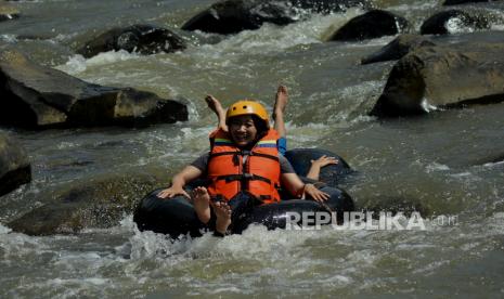 Pengunjung menyusuri aliran sungai menggunakan ban di Desa Wisata Sindangkasih, Cilawu, Kabupaten Garut, Jawa Barat, Ahad (14/3/2021). Destinasi wisata pedesaan yang dikelola oleh masyarakat tersebut menawarkan petualangan menyusuri sungai, spot foto, wahana bermain anak dan rumah kayu bagi pengunjung guna meningkatkan ekonomi warga setempat. 