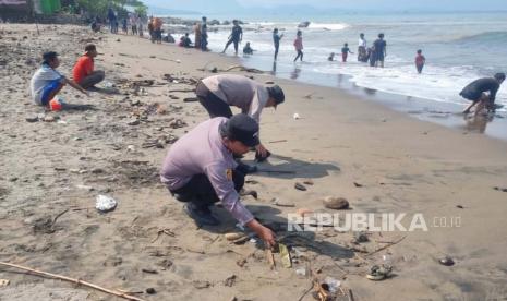 Aparat Polres Sukabumi membersihkan sampah yang ditinggalkan wisatawan di momen libur lebara di Pantai Kadaka, Kecamatan Cikakak Kabupaten Sukabumi, Rabu (26/4/2023).