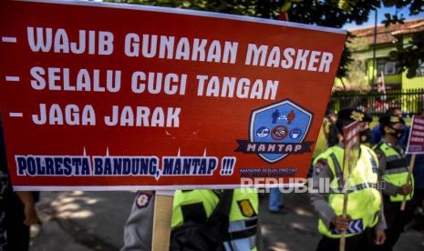 Aparat membawa poster saat sosialisasi protokol kesehatan di area Kantor KPU 