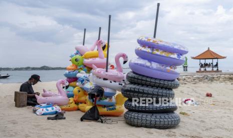 Seorang pria yang menjual dan menyewakan mainan pantai tiup menunggu pelanggan di kawasan wisata di Sanur, Bali, Indonesia, 18 Februari 2022. Menteri Koordinator Bidang Kemaritiman dan Investasi Luhut Binsar Pandjaitan mengatakan uji coba tanpa karantina di Bali dalam seminggu terakhir berhasil mendongkrak kunjungan wisatawan mancanegara (wisman) ke Pulau Dewata. 