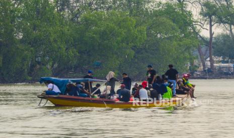 Pengunjung menaiki perahu untuk menuju lokasi konservasi lutung jawa dan wisata mangrove di Muaragembong, Kabupaten Bekasi, Jawa Barat.