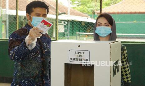 Wakil Gubernur Jawa Timur Emil Elestianto Dardak (kiri) bersama istri Arumi Bachsin memasukkan surat suara di kotak suara TPS 003 Kelurahan Surondakan, Trenggalek,Jawa Timur, Rabu (9/12/2020). Pilkada Trenggalek diikuti dua pasangan calon, yakni pasangan nomor urut 01 Alfan Rianto-Zaenal Fanani dan pasangan nonor urut 02 Mochamad Nur Arifin-Syah Natanegara dengan jumlah pemilih sebanyak 581.880 yang tersebar di 157 desa/kelurahan dan 14 kecamatan.