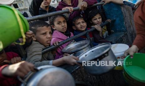 Pengungsi Palestina berkumpul untuk mengumpulkan makanan yang disumbangkan oleh kelompok pemuda amal sebelum sarapan, pada hari kedua bulan suci Ramadhan di Rafah, di selatan Jalur Gaza.