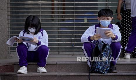 Siswa mengenakan masker wajah untuk membantu mengekang penyebaran virus corona meninjau buku teks di luar sekolah sebelum ujian masuk perguruan tinggi nasional China, yang dikenal sebagai gaokao, di Beijing, Senin, 7 Juni 2021. 