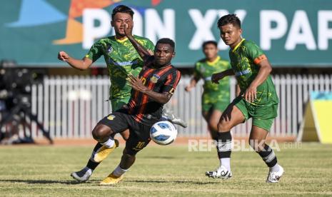 Pesepak bola Papua Ricky Ricardo Cawor (tengah) berebut bola dengan pesepak bola Kalimantan Timur Habibi (kanan) saat pertandingan Semi Final Sepak Bola putra PON Papua di Stadion Mandala, Kota Jayapura, Papua, Selasa (12/10/2021). Papua berhasil mengalahkan Kalimantan Timur dengan skor 5-1. 