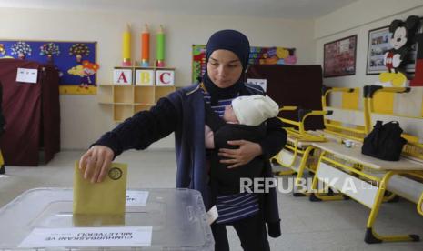 Warga memasukkan surat suara saat mengikuti Pemilu di tempat pemungutan suara di Ankara, Turki.