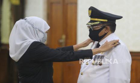 Gubernur Jawa Timur Khofifah Indar Parawansa (kiri) memasang tanda pangkat kepada Wali Kota Blitar Santoso saat pelantikan di Gedung Negara Grahadi, Surabaya, Jawa Timur, Selasa (19/5/2020). Santoso menjadi korban perampokan di rumah dinasnya pada Senin (12/12/2022). 