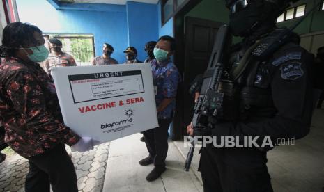 Personel Brimob berjaga saat proses bongkar muatan truk yang mengangkut vaksin COVID-19 Sinovac di kantor Dinas Kesehatan (Dinkes) Provinsi Jawa Timur, Surabaya, Jawa Timur, Senin (4/1/2021). Sebanyak 77.760 dosis vaksin COVID-19 Sinovac tiba di kantor tersebut dan selanjutnya disimpan di ruang pendingin atau cold room. 