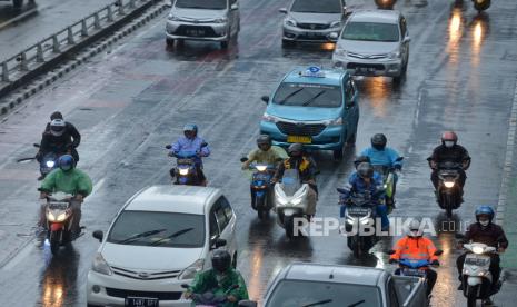 Pengendara motor dengan mengunakan mantel menerjang hujan di Jalan Gatot Subroto, Jakarta.