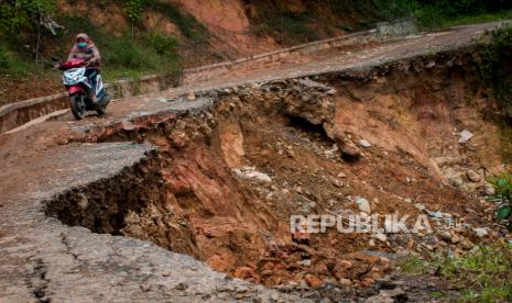 Warga menggunakan kendaraan roda dua melintas di jalan yang longsor di Desa Citorek Kidul, Lebak, Banten, Jumat (8/1/2021). Hujan dengan intensitas tinggi yang terjadi di daerah tersebut mengakibatkan akses jalan utama penghubung Desa Citorek Kidul dan Citorek Tengah terputus akibat longsor pada Rabu (6/1/2021) dan menyebabkan aktivitas ekonomi masyarakat terganggu karena tidak bisa dilalui kendaraan roda empat. 