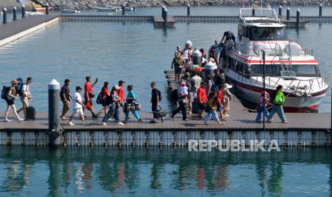 Wisatawan berjalan di dermaga saat akan menaiki kapal cepat di Pelabuhan Sanur, Denpasar, Bali, Jumat (12/4/2024). Penyeberangan wisatawan menggunakan kapal cepat di pelabuhan yang menghubungkan Sanur dengan Pulau Nusa Penida dan Nusa Lembongan itu selama masa libur Lebaran 2024 rata-rata mencapai 7.000 orang pervhari yang didominasi wisatawan domestik atau meningkat jika dibandingkan rata-rata penumpang pada hari biasa yaitu sekitar 4.000 orang. 