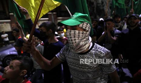 Para pengunjuk rasa memegang bendera dan meneriakkan slogan-slogan menentang Israel selama demonstrasi di pusat kota kota Hebron, Tepi Barat, 11 Mei 2021.