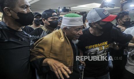 Pimpinan Khilafatul Muslimin Abdul Qadir Baraja (tengah) saat tiba di Mapolda Metro Jaya, Jakarta, Selasa (7/6/2022). Ditreskrimum Polda Metro Jaya menangkap Abdul Qadir Baraja di Lampung setelah ditetapkan sebagai tersangka terkait penyebaran berita bohong yang dapat menimbulkan keonaran dan kegaduhan di tengah masyarakat serta tindak pidana organisasi masyarakat yang bertentangan dengan Pancasila. Republika/Putra M. Akbar 