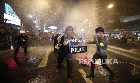 Pengunjuk rasa pro-demokrasi bereaksi ketika polisi anti huru hara menembakkan meriam air selama protes anti-pemerintah di Bangkok, Thailand, 16 Oktober 2020. Pengunjuk rasa pro-demokrasi berkumpul lagi di Bangkok untuk menyimpang dari keputusan pemerintah yang melarang demonstrasi saat pengunjuk rasa menyerukan pengunduran diri warga Thailand Perdana Menteri Prayut Chan-o-cha dan penulisan ulang konstitusi baru dan reformasi monarki.