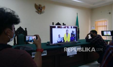 Dua jurnalis menyaksikan dari layar monitor beberapa tahanan politik Papua menjalani sidang daring beragenda pembacaan vonis atas kasus makar di Pengadilan Negeri Balikpapan, Kalimantan Timur, Rabu (17/6/2020). PN Balikpapan menjatuhkan vonis 10 bulan penjara kepada Ferry Kombo, Alex Gobay, Hengky Hilapok dan Irwanus Urobmabin serta vonis 11 bulan penjara kepada Agus Kossay, Buchtar Tabuni dan Steven Itlay karena terlibat kasus tindakan makar terkait unjuk rasa menolak rasialisme di Papua pada Agustus 2019