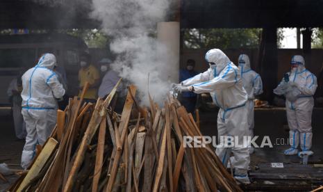 Anggota keluarga, yang mengenakan Alat Pelindung Diri (APD), melakukan upacara terakhir untuk korban COVID-19 selama pemakaman mereka di tempat kremasi di New Delhi, India,  Kamis (29/4). Delhi melaporkan 25.986 kasus baru, 368 kematian dalam 24 jam terakhir dan terus berjuang dengan suplai oksigen.