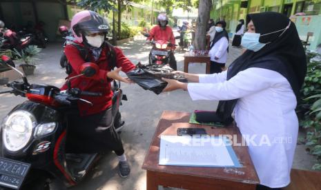 Menag: Insentif Guru Madrasah Bukan PNS Segera Cair. Guru meminjamkan buku kepada wali murid secara lantatur di halaman Madrasah Ibtidaiyah Negeri 2 Kediri, Jawa Timur, Senin (26/7/2021). Peminjaman buku secara lantatur (layanan tanpa turun) tersebut guna menunjang pembelajaran daring seiring Pemberlakuan Pembatasan Kegiatan Masyarakat (PPKM). 