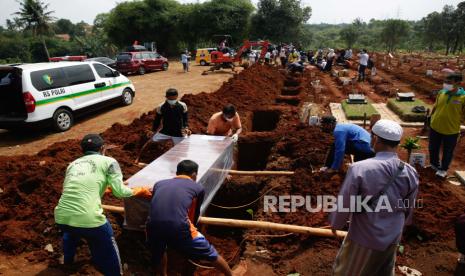  Pekerja membawa peti mati seseorang yang meninggal karena komplikasi penyakit COVID-19 saat pemakaman di pemakaman di Depok.  Kementerian Kesehatan (Kemenkes) mengatakan, pelaporan kasus kematian akibat Covid-19 yang dilakukan daerah tidak bersifat realtime dan merupakan akumulasi dari bulan-bulan sebelumnya. Satuan Tugas (Satgas) Covid-19 mengatakan, sinkronisasi membuat kesenjangan angka kematian bisa terungkap.