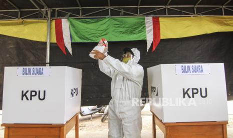 Petugas KPPS berpakaian baju hazmat dan alat pelindung diri (APD) menyemprotkan cairan disinfektan di Tempat Pemungutan Suara (TPS) 13, Cipayung, Depok, Jawa Barat, Rabu (9/12/2020). TPS di Kota Depok menerapkan protokol kesehatan pada Pilkada Serentak 2020 di masa Pandemi COVID-19.