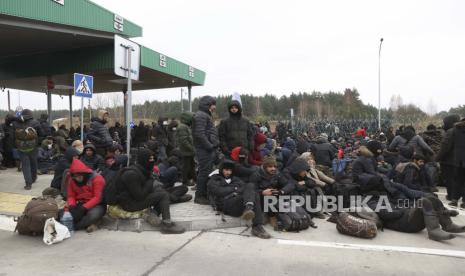 Para migran berkumpul di depan pagar kawat berduri dan tentara Polandia di pos pemeriksaan Kuznitsa di perbatasan Belarus-Polandia dekat Grodno, Belarus, pada Senin, 15 November 2021. Para pengungsi di Belarusia sedih karena gagal mencari harapan baru di Eropa.