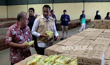 Pemimpin Wilayah Perum Bulog Jawa Tengah, Akhmad Kholisun (kiri) bersama Wakil Ketua Satgas Pangan Ditreskrimsus Polda Jawa Tengah, AKBP Rosyid Hartanto meninjau minyak goring di gudang Bulog Tambak Aji, Semarang, Rabu (15/2).