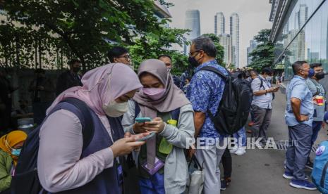 Orang-orang memeriksa ponsel mereka saat berada di luar di tengah kekhawatiran gempa susulan menyusul gempa bumi di kawasan bisnis di Jakarta, Indonesia, 08 Desember 2022. Menurut Badan Meteorologi Indonesia (BMGK), gempa berkekuatan 5,8 melanda tenggara Sukabumi, provinsi Jawa Barat. Gempa dirasakan di gedung-gedung bertingkat di ibu kota dan memaksa para pekerja dievakuasi.