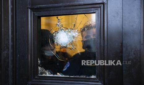 Polisi Capitol AS melihat dari balik pecahan kaca di pintu rotunda Capital di Front Timur Capitol AS setelah pengunjuk rasa pro-Trump menyerbu lapangan yang mengarah ke kekacauan, di Washington, DC, AS, 06 Januari 2021. Berbagai kelompok pendukung Trump telah membobol Capitol AS dan melakukan kerusuhan saat Kongres bersiap untuk bertemu dan mengesahkan hasil pemilihan Presiden AS 2020.