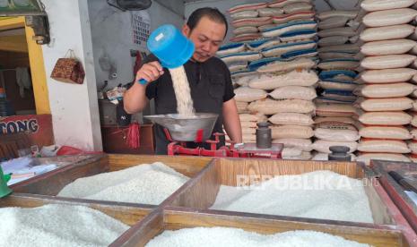 Seorang pedagang beras di Pasar Baru Indramayu, Hadi (46 tahun) sedang menimbang beras, Senin (9/10/2023). 