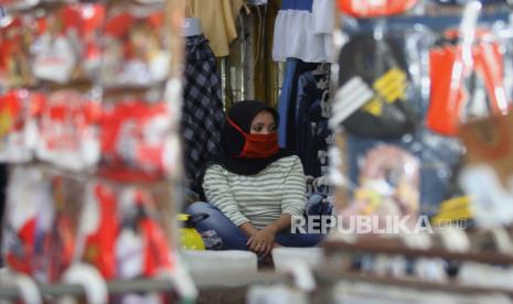 Karyawan memakai masker saat menjaga salah satu toko busana di Pasar Kapasan, Surabaya, Jawa Timur