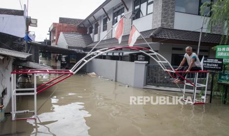 Warga duduk di atas gapura kampung saat banjir di Kampung Joyotakan, Solo, Jawa Tengah, Jumat (17/2/2023). Berdasarkan data Badan Penanggulangan Bencana Daerah (BPBD) Kota Solo sebanyak 21.846 jiwa dari 15 Kelurahan di Kota Solo terdampak banjir akibat meluapnya sejumlah anak sungai Bengawan Solo. 