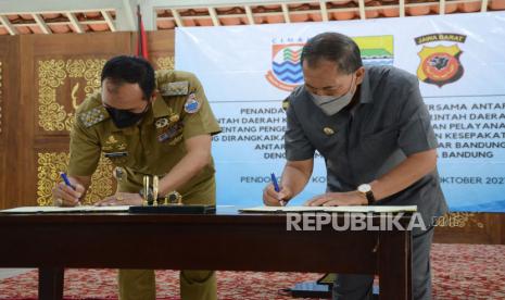 Wali Kota Bandung Oded M Danial (kanan) dan Plt Wali Kota Cimahi Ngatiyana melakukan penandatanganan kesepakatan bersama antara Pemerintah Daerah Kota Bandung dengan Pemerintahan Daerah Kota Cimahi tentang pengembangan potensi daerah dan pelayanan publik di Pendopo Kota Bandung, Senin (4/10). Kerjasama tersebut merupakan singkronisasi dan koordinasi antara dua wilayah termasuk untuk mengatasi kendala di lintas batas seperti banjir yang kerap terjadi saat musim hujan.