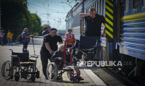 Petugas polisi membantu seorang wanita lanjut usia naik ke kereta evakuasi setelah dia dievakuasi dari daerah Lysychansk di Pokrovsk di Ukraina timur, Sabtu 11 Juni 2022.