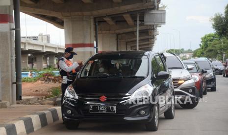 Petugas melakukan pengecekan kepada pengendara dengan plat nomor luar daerah yang melintasi Check Point PSBB di kawasan Kalimalang, Jakarta, Selasa (26/5). Pemerintah Provinsi DKI Jakarta menerapkan aturan penggunaan Surat Izin Keluar-Masuk (SIKM) untuk membatasi warga yang keluar masuk Jakarta pada masa arus balik