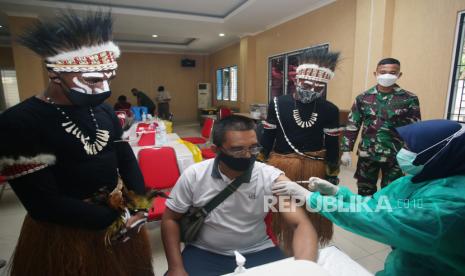 Dua anggota TNI Angkatan Darat (AD) Bintara Otonomi Khusus asal Papua dengan menggunakan pakian adat menemani dan menghibur warga yang mengikuti vaksinasi COVID-19 di Koramil Serpong, Serpong, Tangerang Selatan, Banten, Kamis (19/8/2021). Kehadiran Bintara Otonomi Khusus asal Papua tersebut menjadi daya tarik sendiri bagi warga sekitar untuk mengikuti Vaksinasi COVID-19 dosis pertama. 